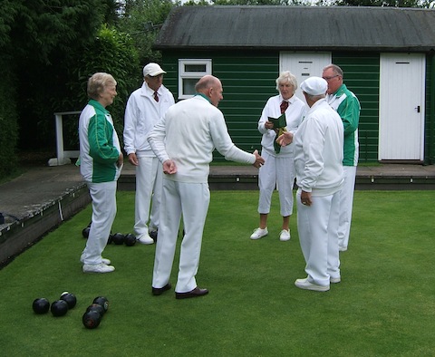 Viv Smith in Castle Green's green and white uniform at left, Jim Horwood with green collar in the centre, and Brian West at right, conferring with opposing Billingshurst team members at the start of the game.