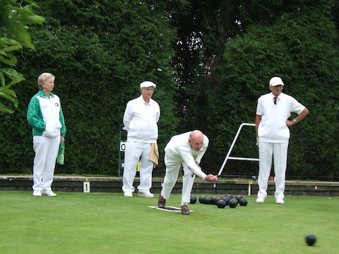 Jim Horwood bowling, while Viv Smith (in green) watches.