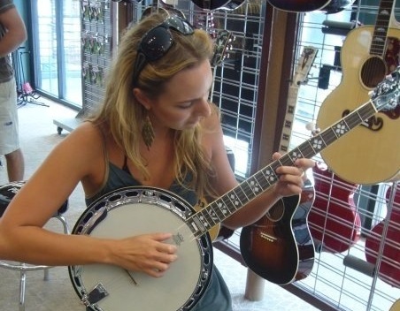 Emma Stevens trying out a banjo, just one of the six stringed instruments she plays