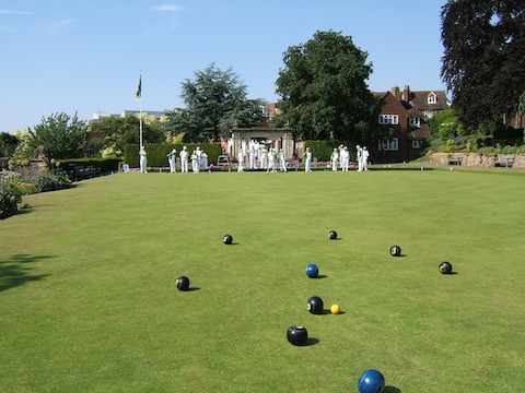 CGBC bowlers, with green facings, and the Saltdean bowlers, in white, against the backdrop of the war memorial.