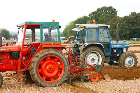 Tractors ploughing straight furrows.