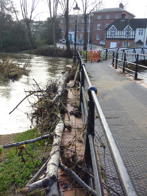 Debris lays against the footbridge at Millmead.