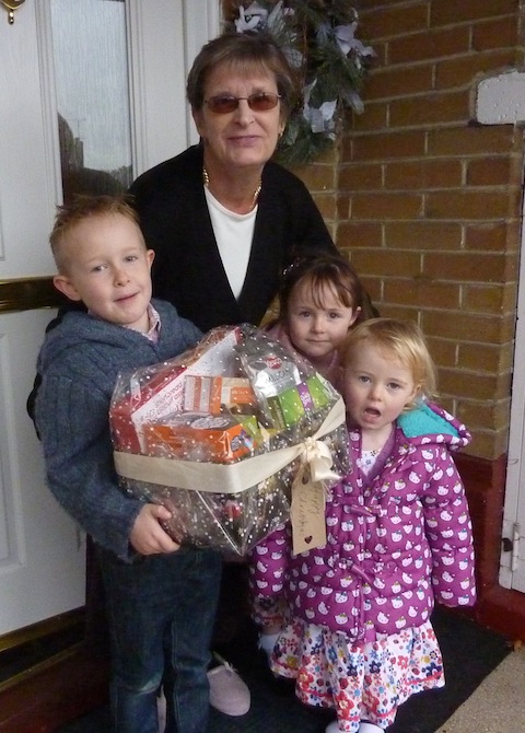 Pat Rawlings receives a Christmas hamper from Ethan, Jasmine and Zoe – all members of Guildford City Boys & Girls Football Club.
