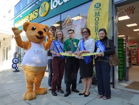 Pictured at the opening of the store, from left: Hector the halow bear; Kyle a young volunteer with halow; Emma Robinson from Voluntary Action South West Surrey; store manager Jamie Wheeler; and Denise Graves and Monica Vidal, also from Voluntary Action South West Surrey.