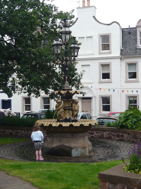 A little girl admires the water fountain, the bunting is up for gala week.