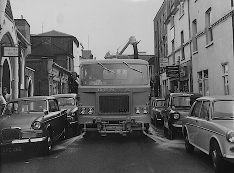 A Dennis-made street washing vehicle passes along Commercial Road in about the early 1970s. The view looks  towards North Street. The buildings on the right disappeared when the Friary centre was developed. Some of the buildings on the right have been long gone too. Those that do remain are soon to be demolished. Does anyone know when the Baptist church was closed and pulled down?