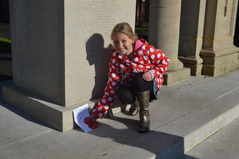 Carys Bailey, aged 9, places a card she had drawn at the war memorial.