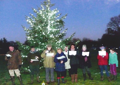 The choir from St Mary's Church on Wood Street Village green carol singing.