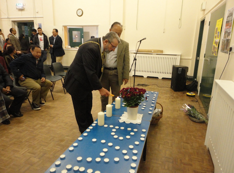 The Mayor of Guildford, David Elms, lights a candle flanked by Sham Gurung.