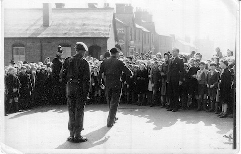 Field Marchall Bernard Mongomerie strides out from Stoughton Barracks towards headmaster Mr Hardy, while children look on.