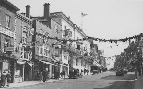 Guildford High Street pictured in 1935 at the time of Geore V's silver jubilee. On the far left is the office of Clarke Gammon & Emerys.