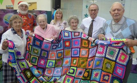 An example of what regularly goes on at the Park Barn Social Centre is this blanet made up of 117 square and made by a client, Jean, aged 88. It was raffled and made £111 for the centre's funds. Pictured are Alice, Jean and Ivy, with Geoff, far rigjht, volunteer Barrie (wearing Santa hat) and Westbrough ward councillor Julia McShane and Cllr Tony Rooth.