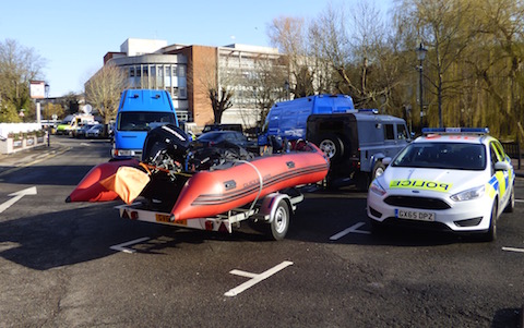 Police vehicles and a dinghy in Millmead car park.