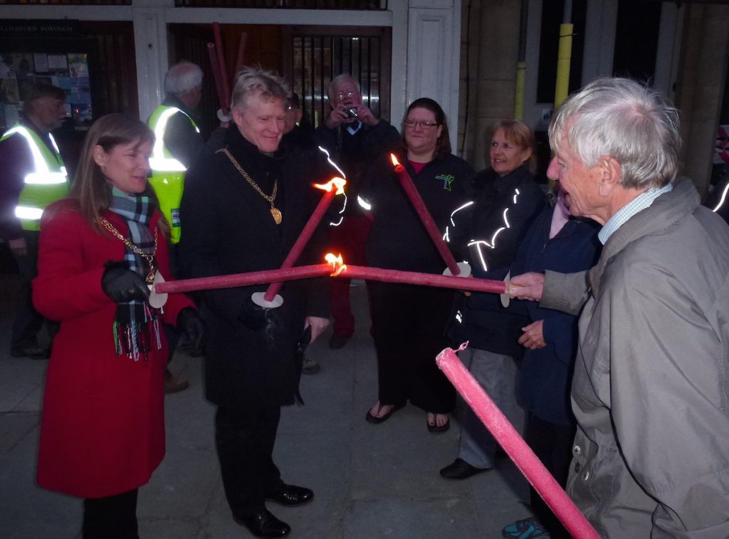 The Mayor of Guildford uses her torch to light another at the Guildhall before the procession headed off.