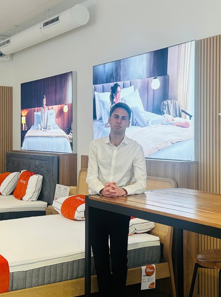 Emma Sleep Guildford manager John Leverton in-store sitting on a bed.